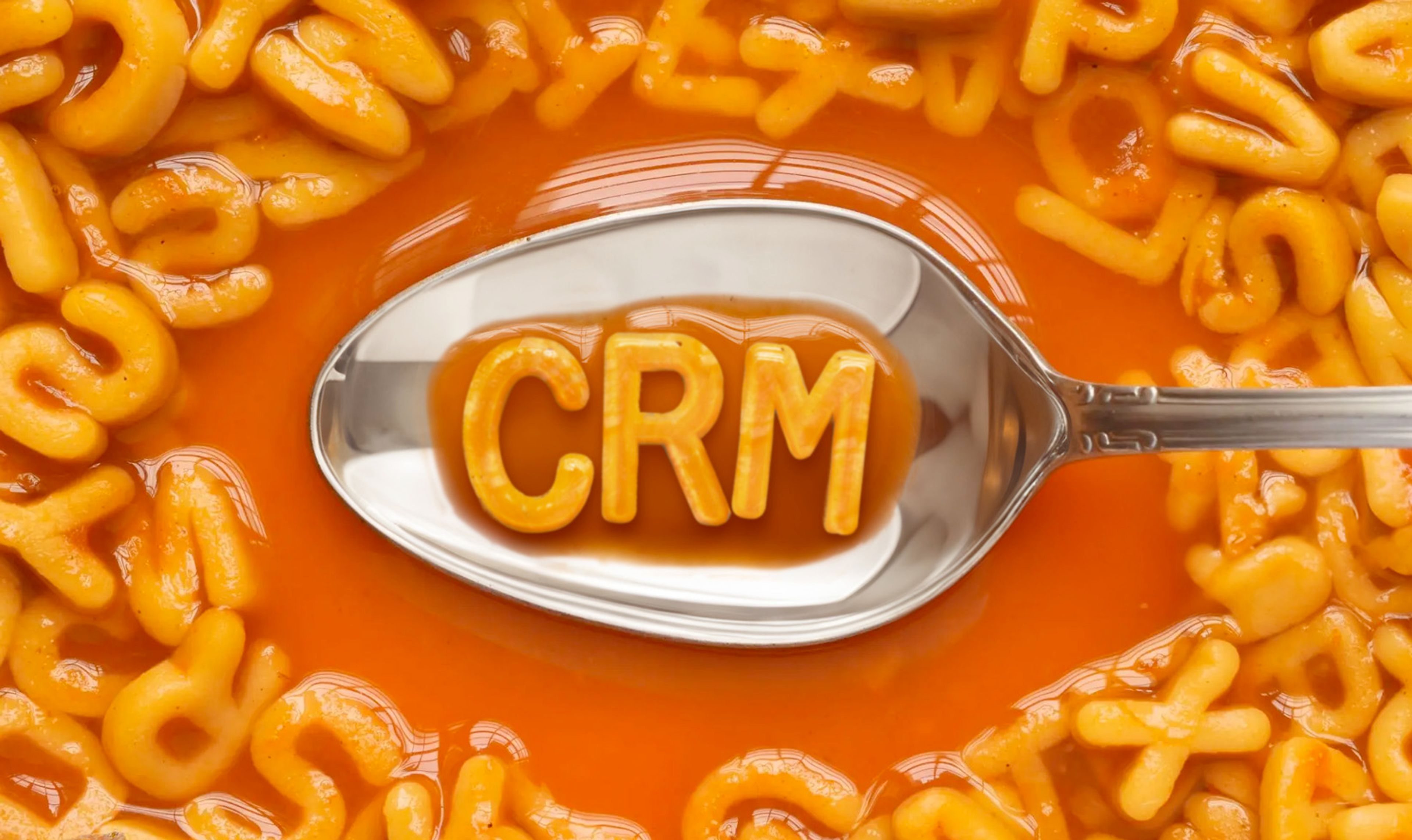 Alphabet soup with a spoon containing noodles in the shape of letters reading "CRM"