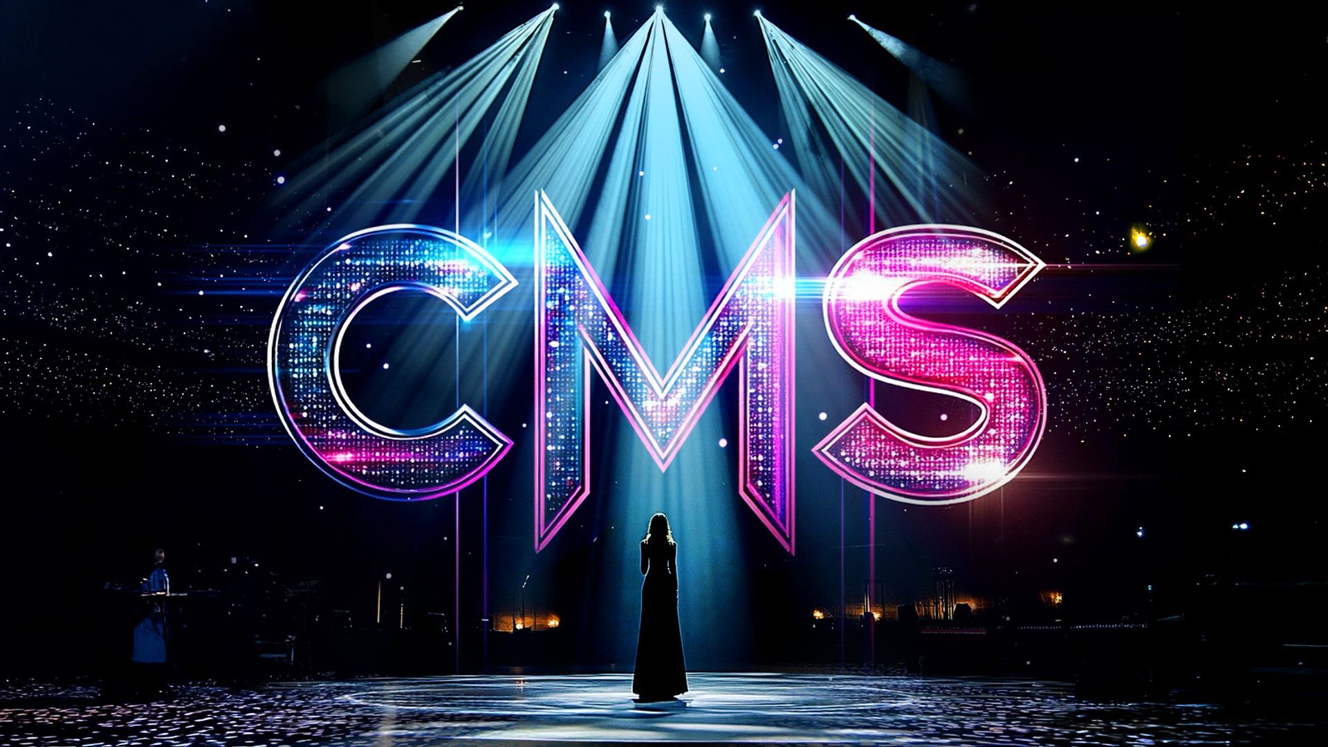 In a Eurovision-like scene, the letters "CMS" hanging suspended in the air under stage spotlights, with mirrorball glitter on each of the letters. Below, a single female singer is taking the spotlight in front a large audience.