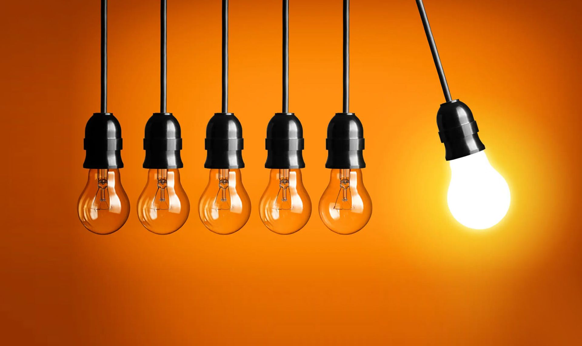 A row of lightbulbs hanging, all are off but one is lit and swinging out