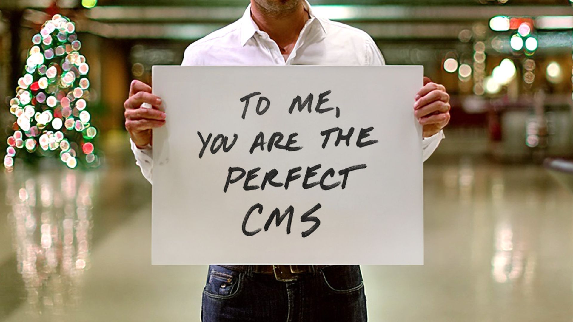 A man holding a sign that says "To me, you are the perfect CMS"
