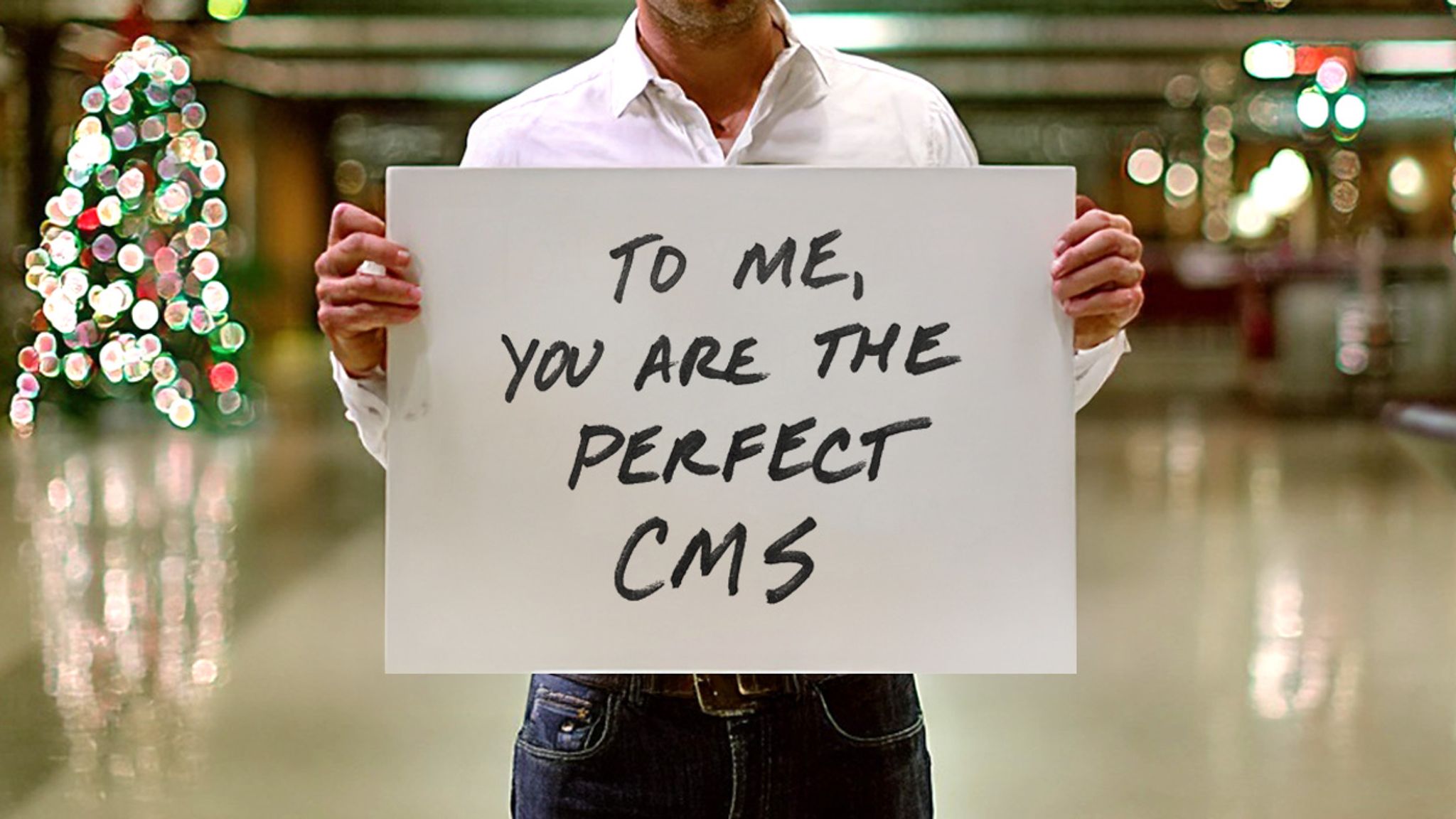 A man holding a sign that says "To me, you are the perfect CMS"