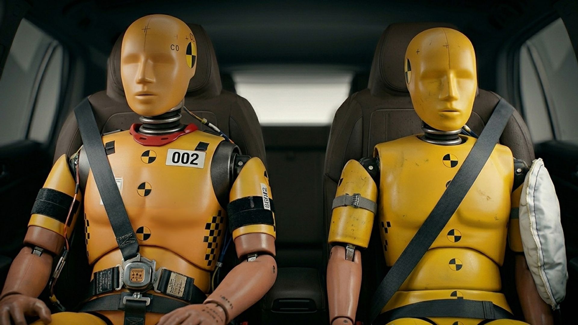 Two crash test dummies in a car with seatbelts on